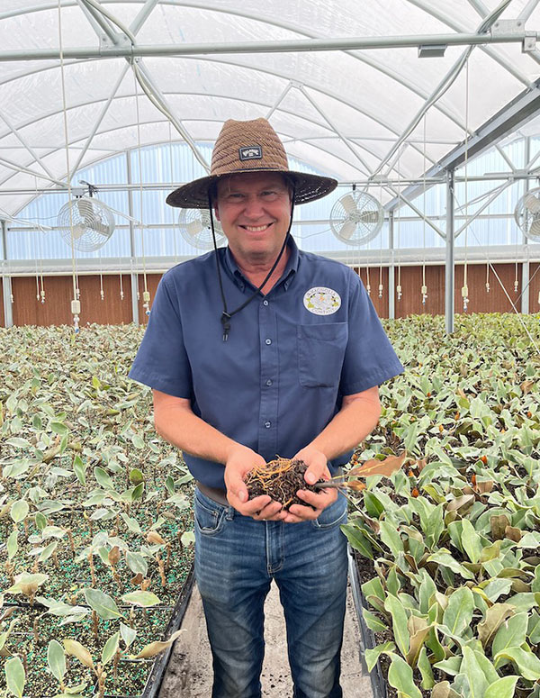 Matt Holding Magnolia Seedling in Greenhouse